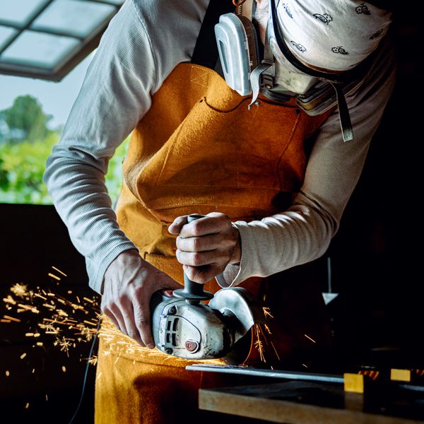 A person using an angle grinder, with sparks flying