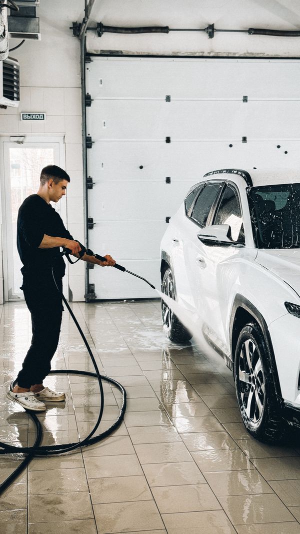A person cleaning a car with a pressure washer
